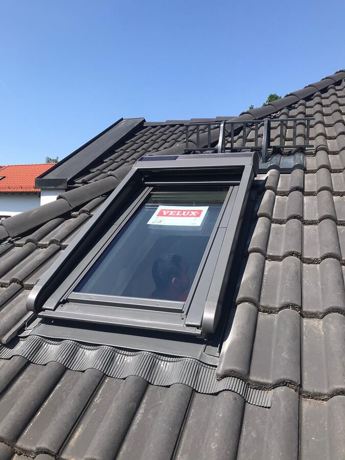 Neu eingebautes Dachflächenfenster in einem grauen Ziegeldach