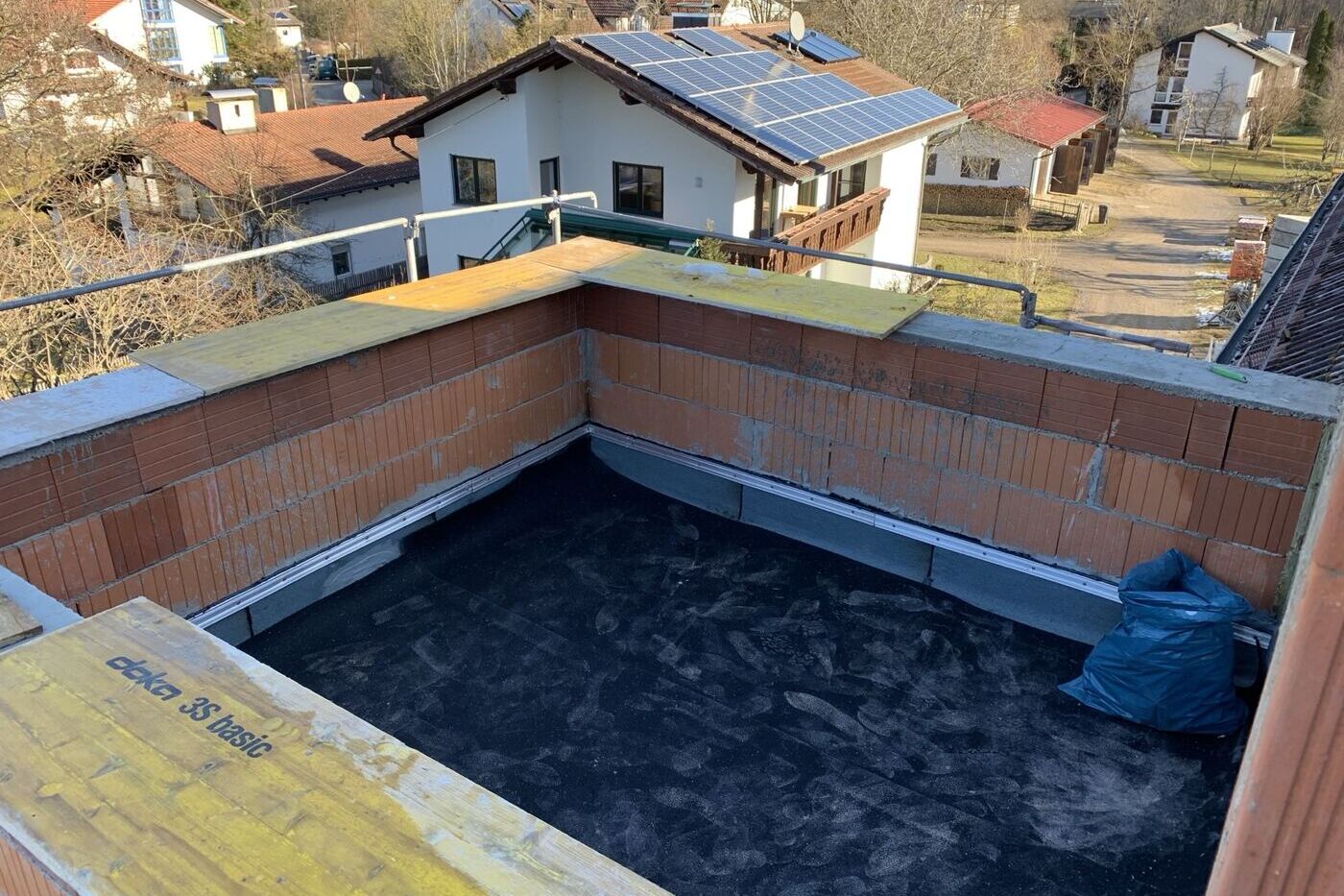 Loggia im Rohbau mit roher Abdichtungsbahn und offenem Ziegelmauerwerk